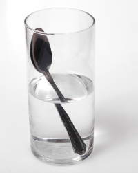 Refraction of light in a glass of water causes the image of part of the spoon to appear in a different place